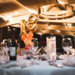 Premier plan d'une table ronde élégamment dressée dans un restaurant pour la célébration d'un anniversaire, immortalisée par la photographe Nathalie Mota.
