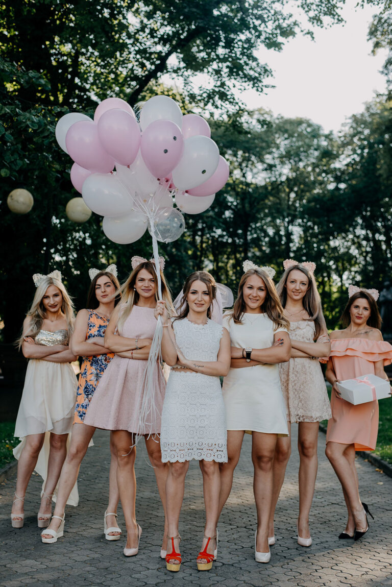 Photo de groupe des amies de la mariée tenant un bouquet de ballons roses et blancs.